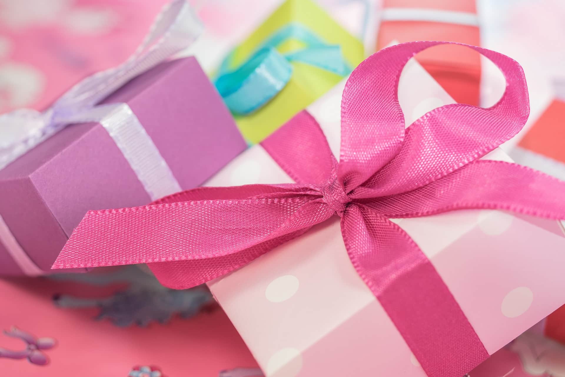 close up of pink and purple square gift boxes tied with ribbon